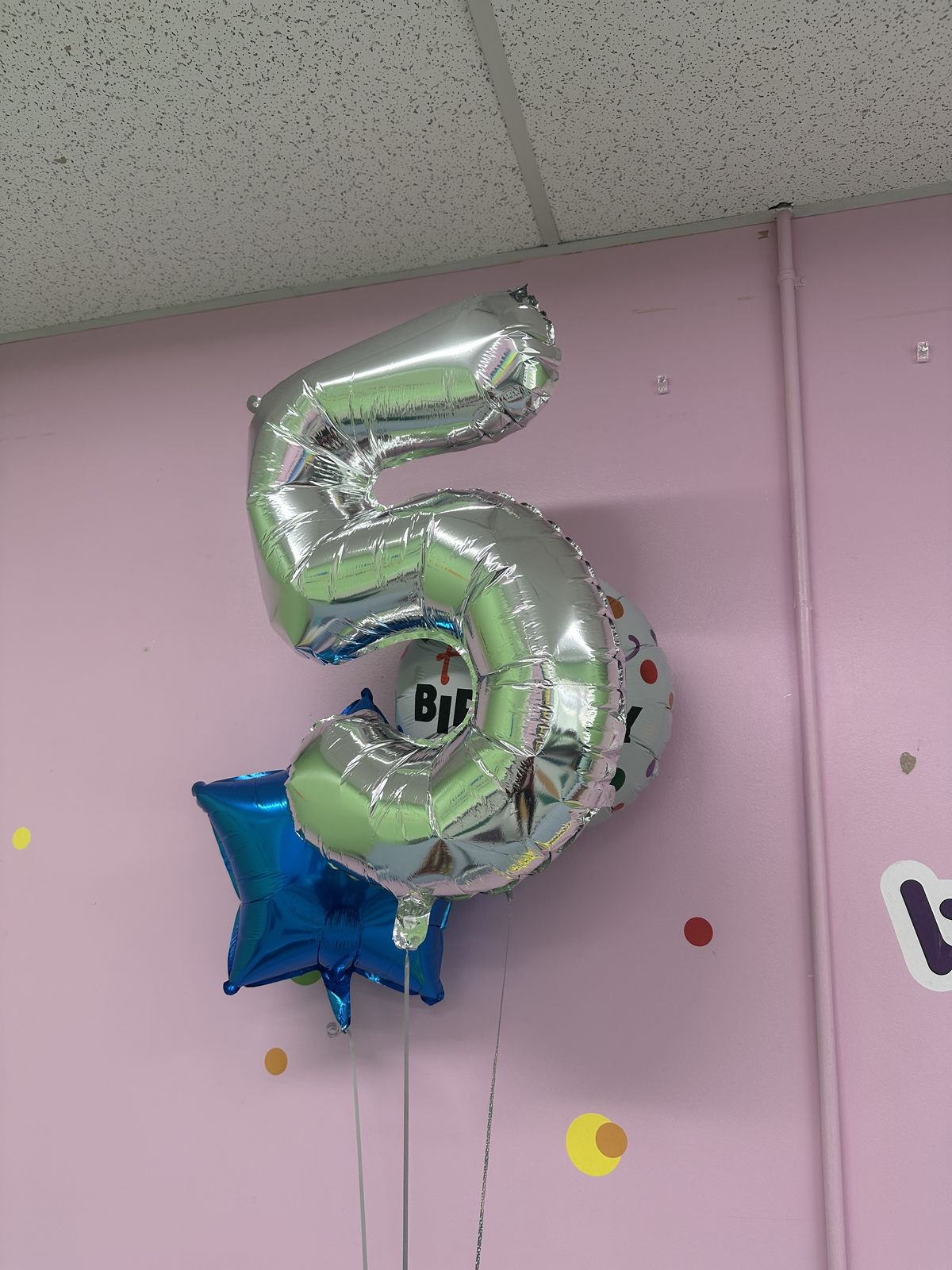 Large silver number five balloon on party wall