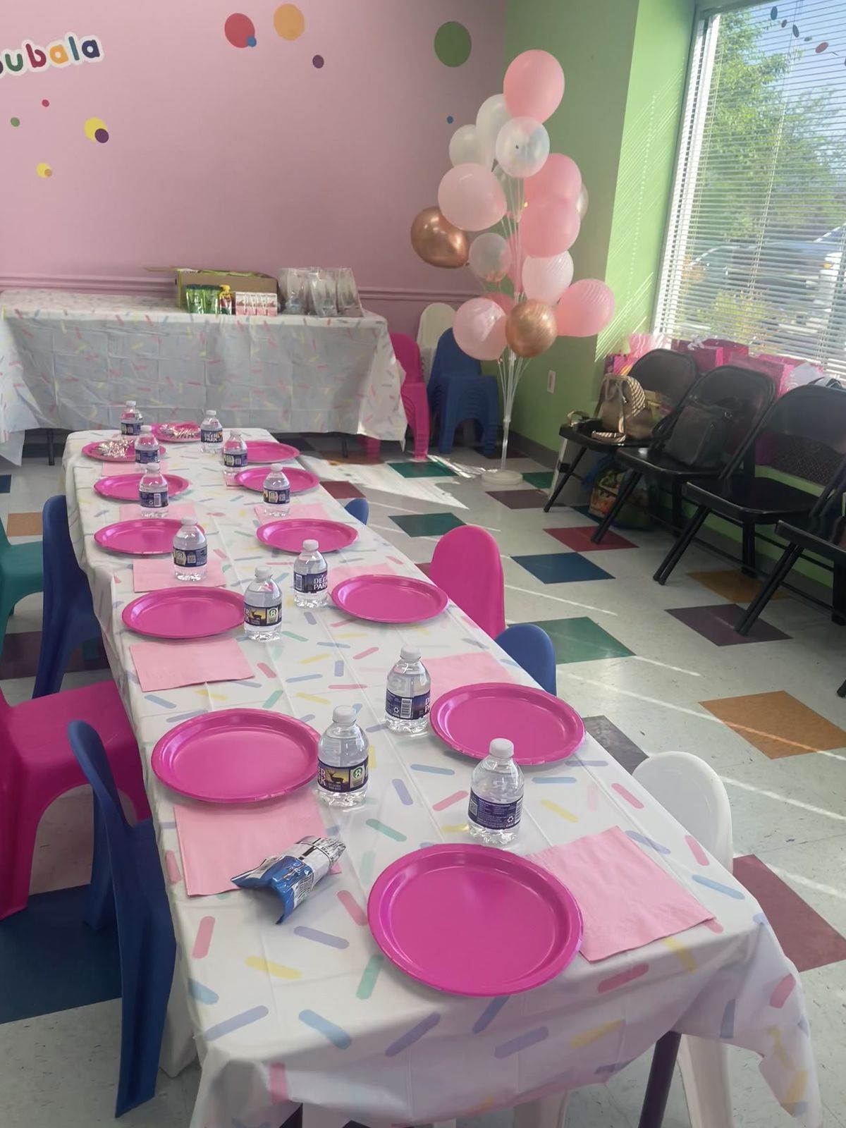 Pink party table with balloon decorations by the window